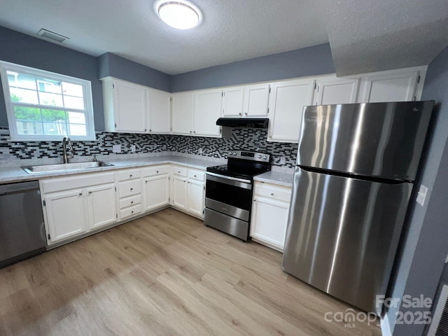 kitchen featuring sink, stainless steel appliances, light hardwood / wood-style floors, a textured ceiling, and white cabinets