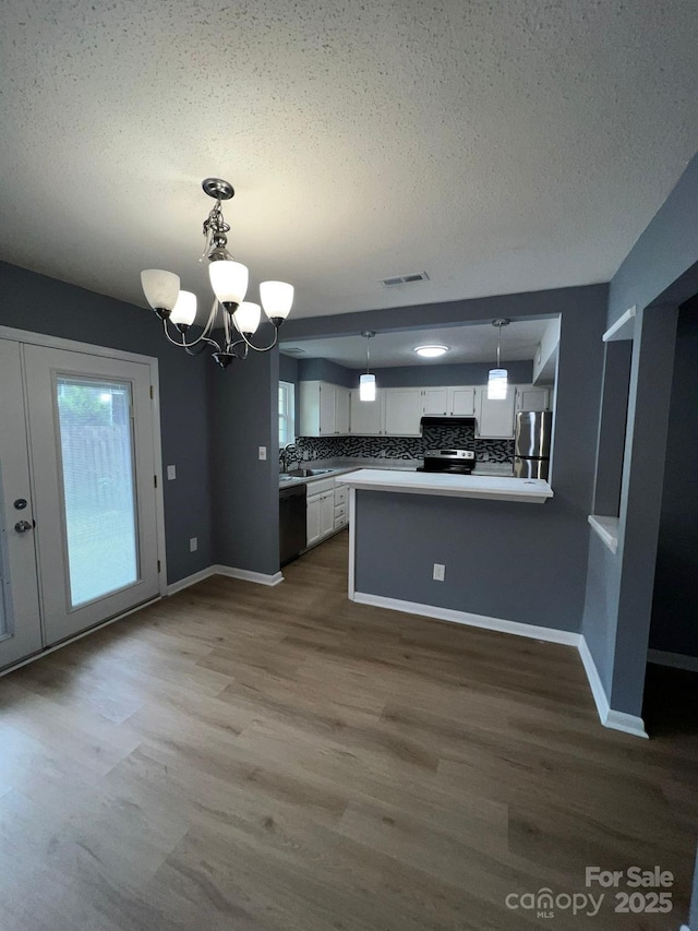 kitchen featuring white cabinets, decorative backsplash, decorative light fixtures, kitchen peninsula, and a chandelier