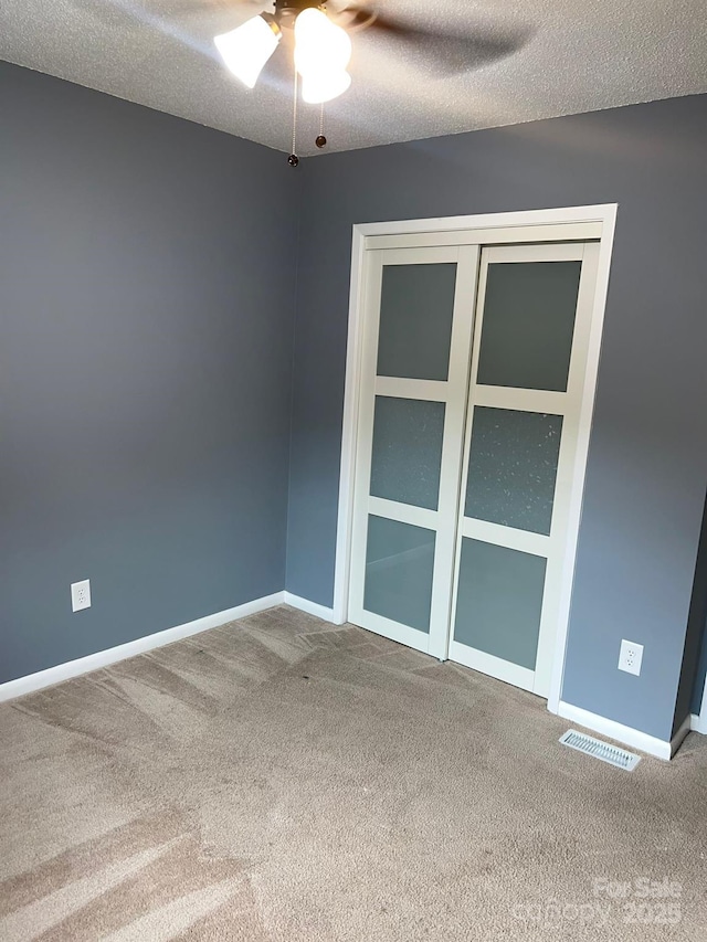 carpeted empty room featuring ceiling fan and a textured ceiling