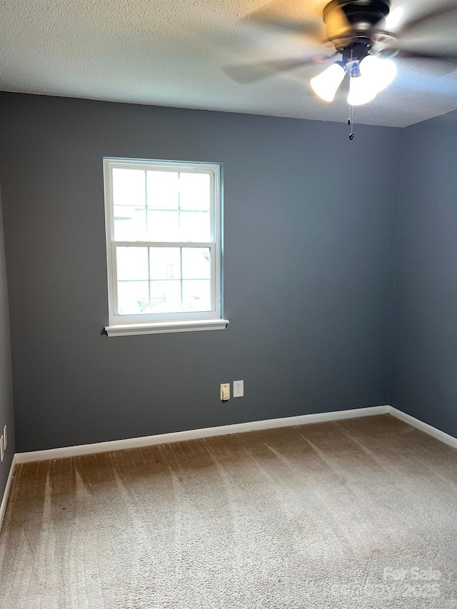 carpeted empty room featuring ceiling fan and a textured ceiling