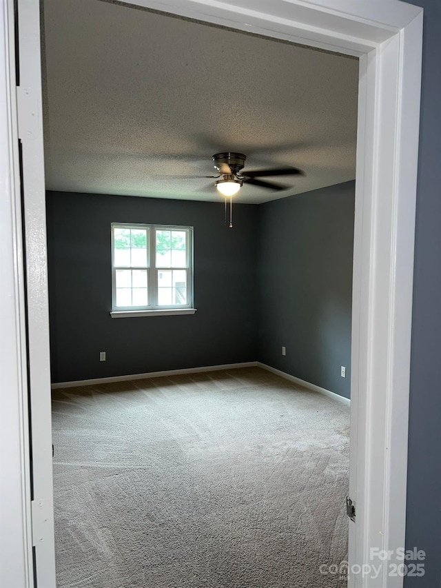 carpeted empty room with ceiling fan and a textured ceiling