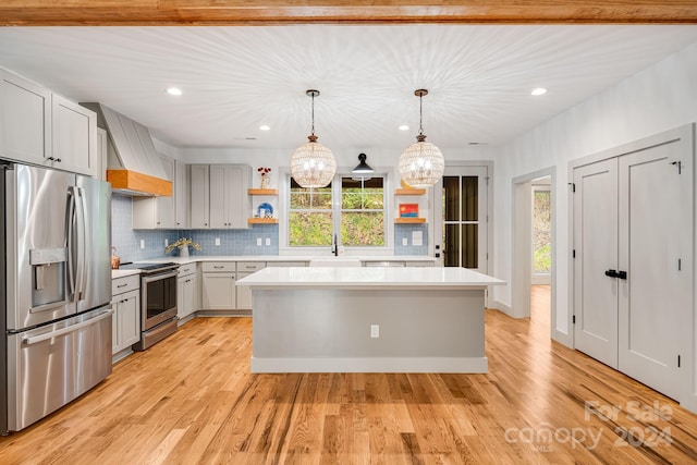 kitchen with a healthy amount of sunlight, stainless steel appliances, decorative light fixtures, and light hardwood / wood-style floors