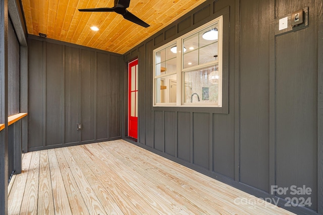 exterior space featuring ceiling fan, wood ceiling, wooden walls, and light hardwood / wood-style flooring