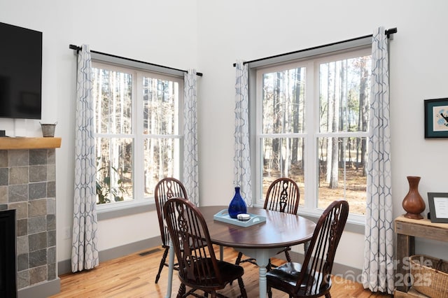 dining space featuring a fireplace, a healthy amount of sunlight, and light hardwood / wood-style flooring