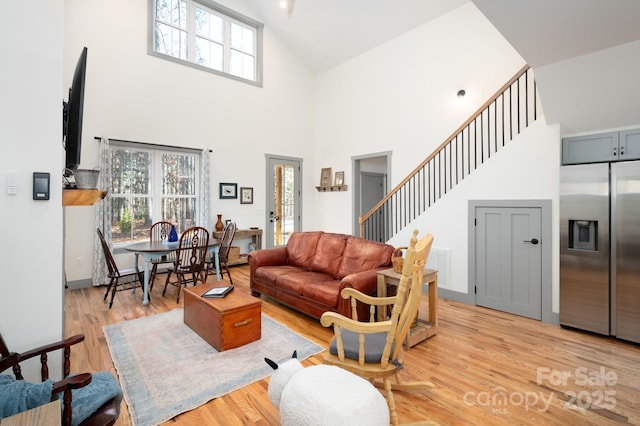 living room with a towering ceiling and light hardwood / wood-style floors