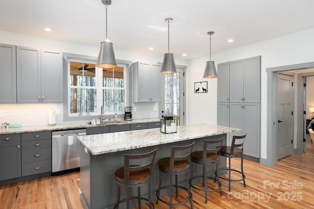 kitchen with gray cabinetry, dishwasher, a center island, and sink