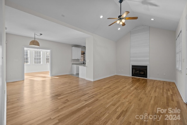 unfurnished living room with ceiling fan, a fireplace, light hardwood / wood-style floors, and vaulted ceiling