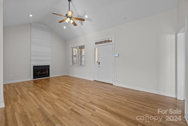 unfurnished living room with ceiling fan, a fireplace, lofted ceiling, and light hardwood / wood-style flooring