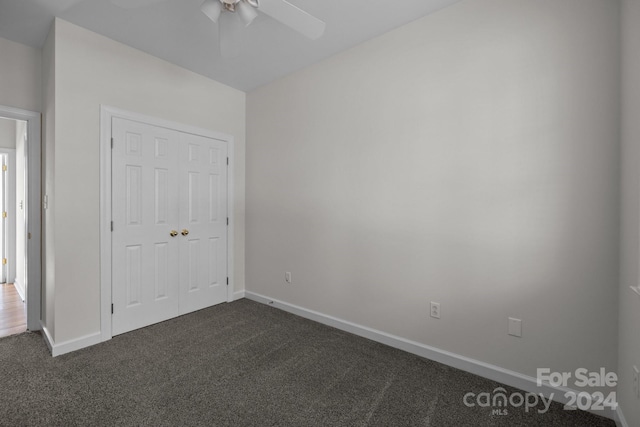 unfurnished bedroom featuring dark colored carpet, ceiling fan, and a closet