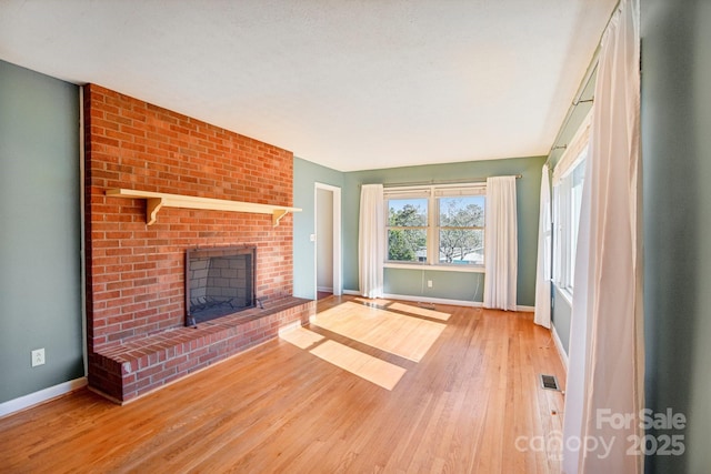 unfurnished living room featuring hardwood / wood-style floors and a brick fireplace