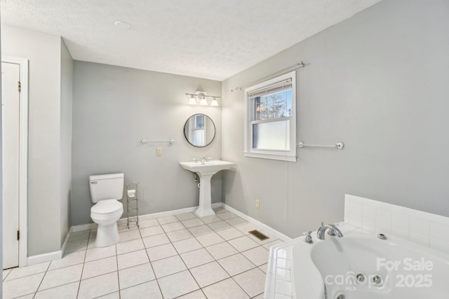 bathroom with a washtub, tile patterned floors, a textured ceiling, and toilet