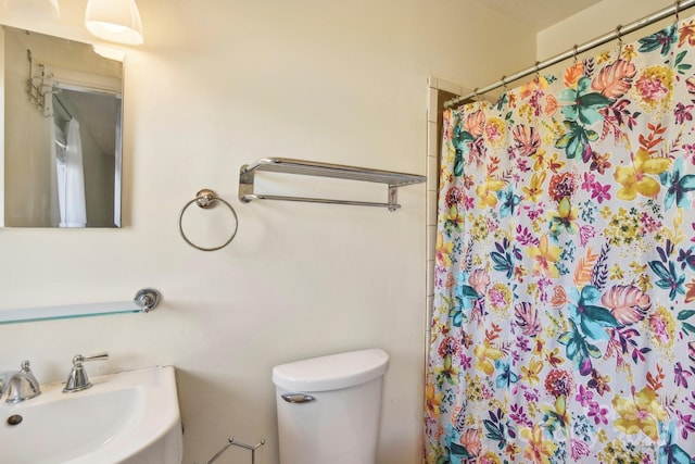 bathroom featuring a shower with curtain, toilet, and sink