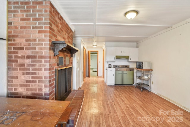 kitchen with light hardwood / wood-style floors, stainless steel range oven, white cabinetry, and a fireplace