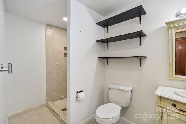 bathroom featuring tile patterned flooring, vanity, toilet, and tiled shower