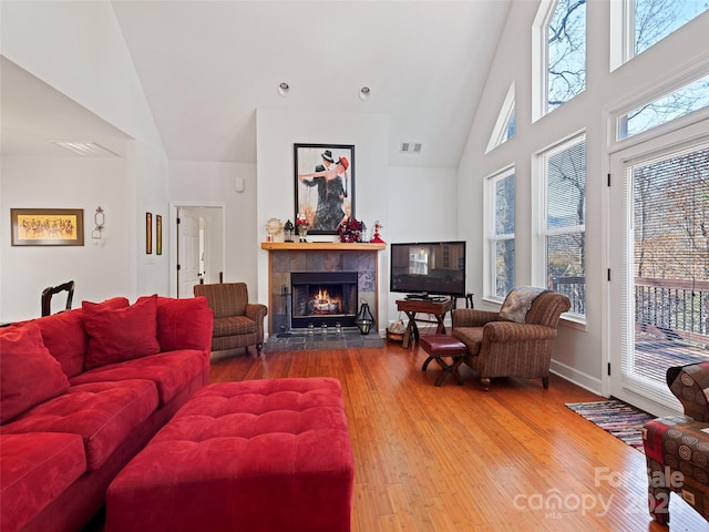 living room with a fireplace, high vaulted ceiling, and wood-type flooring