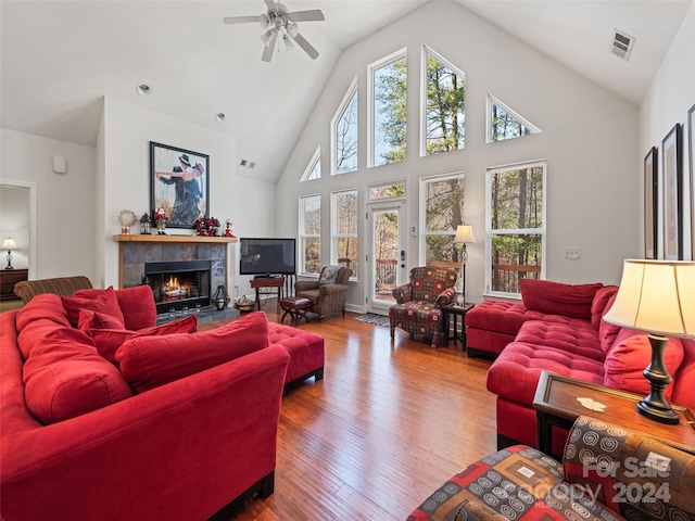 living room with a tiled fireplace, ceiling fan, high vaulted ceiling, and hardwood / wood-style flooring