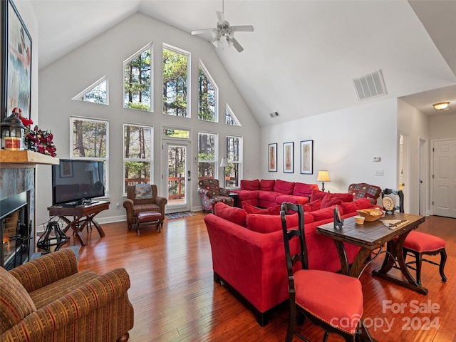 living room featuring a fireplace, wood-type flooring, high vaulted ceiling, and ceiling fan