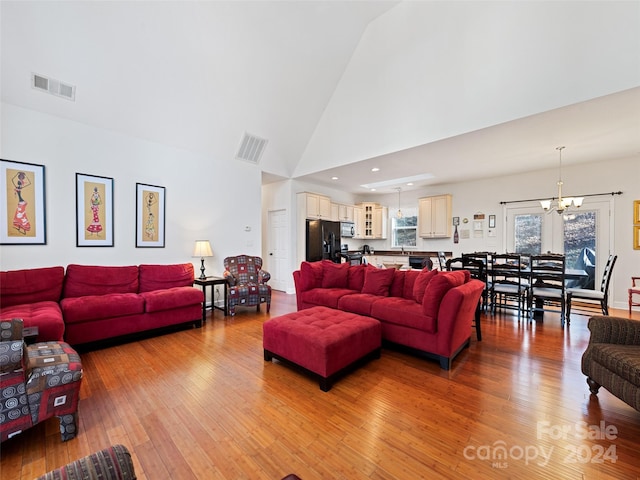 living room with light hardwood / wood-style flooring, high vaulted ceiling, and a notable chandelier