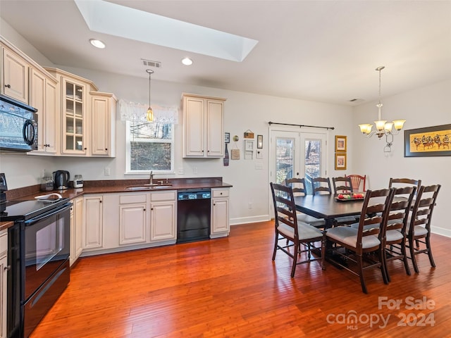 kitchen with black appliances, sink, hanging light fixtures, and a skylight