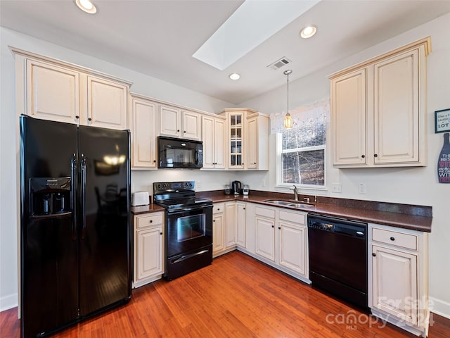 kitchen featuring light wood-type flooring, sink, a skylight, and black appliances