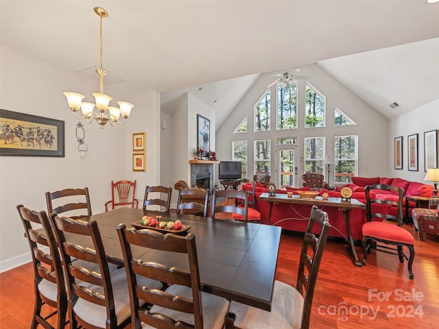 dining area with hardwood / wood-style floors, high vaulted ceiling, and ceiling fan with notable chandelier