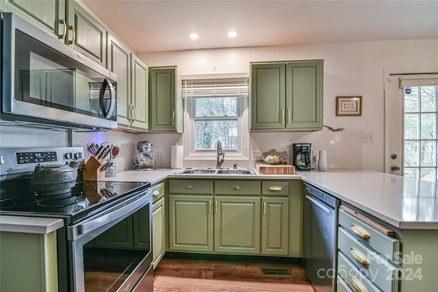 kitchen featuring kitchen peninsula, appliances with stainless steel finishes, green cabinets, and sink