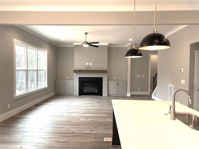 unfurnished living room with a large fireplace, crown molding, visible vents, and a sink