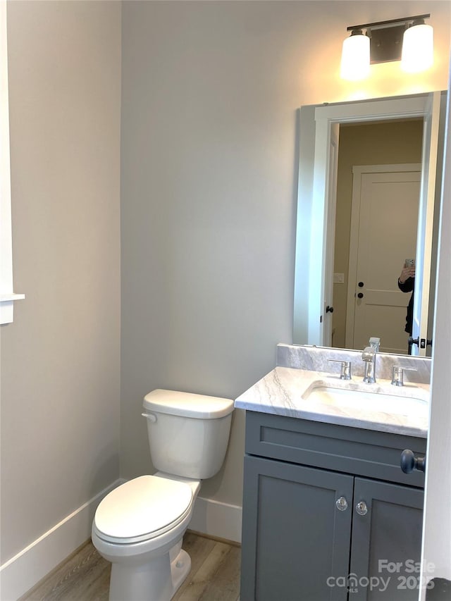 bathroom featuring toilet, wood finished floors, vanity, and baseboards