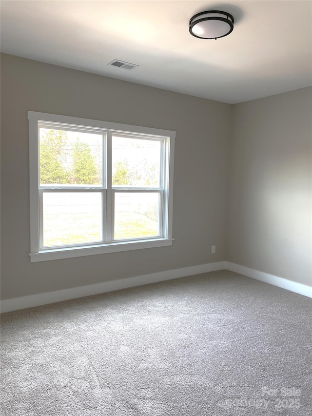 unfurnished room with carpet, visible vents, and baseboards