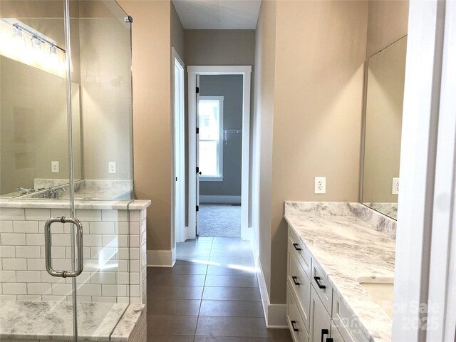 full bath featuring a stall shower, vanity, baseboards, and tile patterned floors