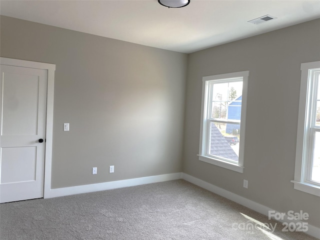 carpeted spare room with visible vents and baseboards