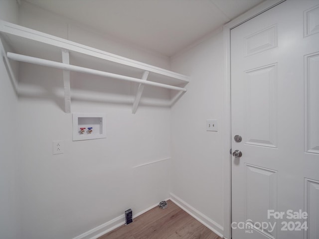 clothes washing area with hardwood / wood-style floors and washer hookup