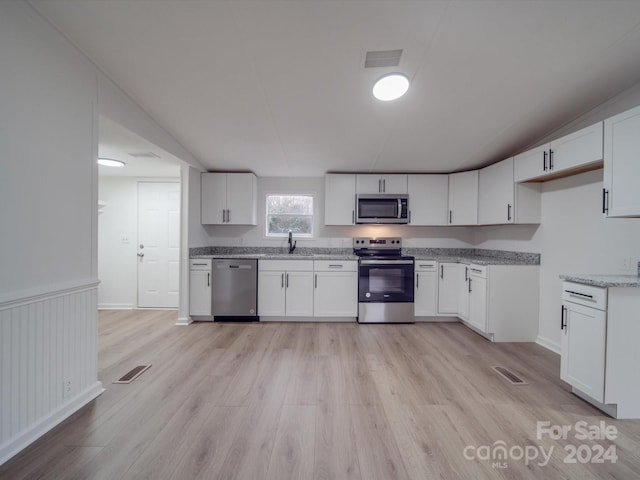 kitchen featuring light stone countertops, stainless steel appliances, sink, light hardwood / wood-style floors, and white cabinetry