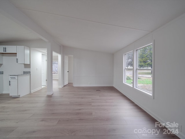 unfurnished living room with light wood-type flooring and lofted ceiling