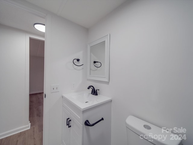 bathroom featuring toilet, vanity, and hardwood / wood-style flooring