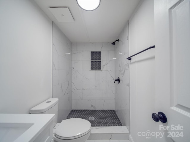 bathroom featuring a tile shower, vanity, and toilet