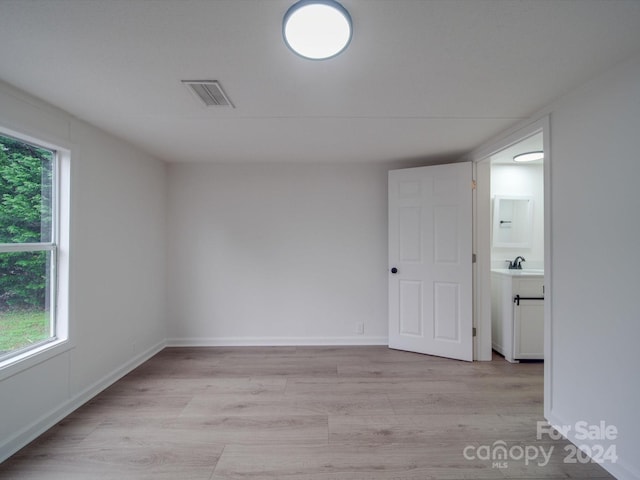 empty room featuring light wood-type flooring, plenty of natural light, and sink