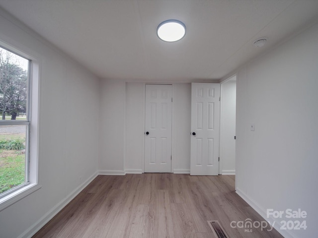 empty room with a wealth of natural light and light hardwood / wood-style flooring