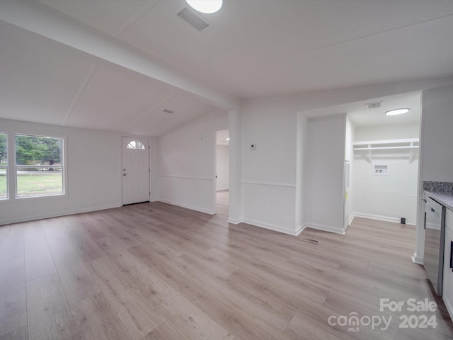 unfurnished living room with vaulted ceiling with beams and light wood-type flooring