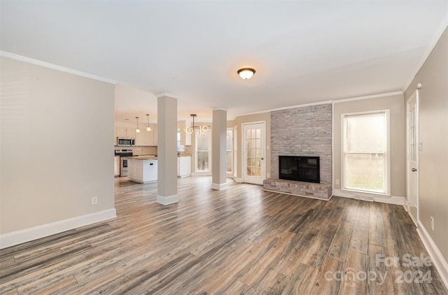 unfurnished living room featuring hardwood / wood-style floors, a notable chandelier, crown molding, and a fireplace