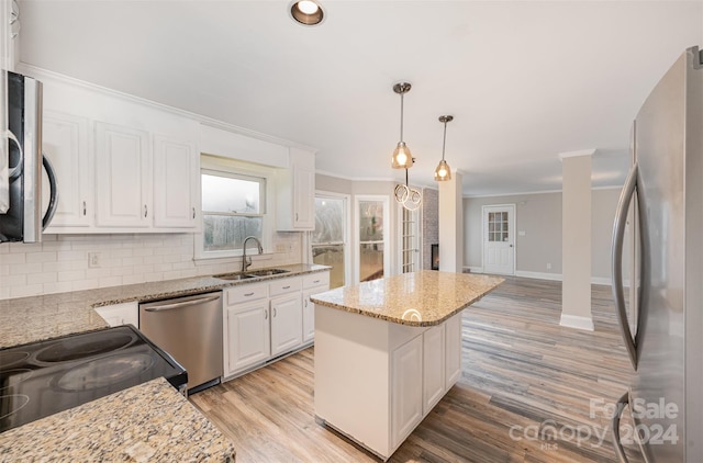 kitchen featuring white cabinetry, sink, light hardwood / wood-style flooring, pendant lighting, and appliances with stainless steel finishes