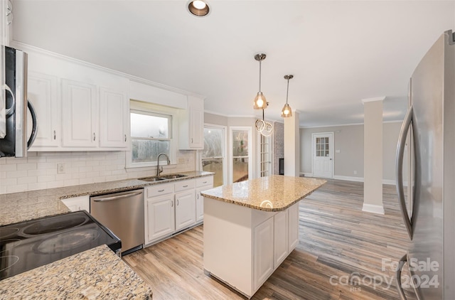 kitchen featuring white cabinetry, sink, hanging light fixtures, stainless steel appliances, and light hardwood / wood-style flooring