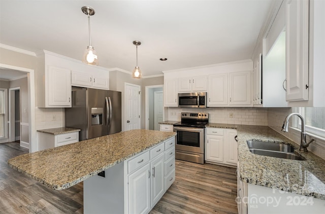 kitchen featuring stainless steel appliances, sink, white cabinets, a kitchen island, and hanging light fixtures