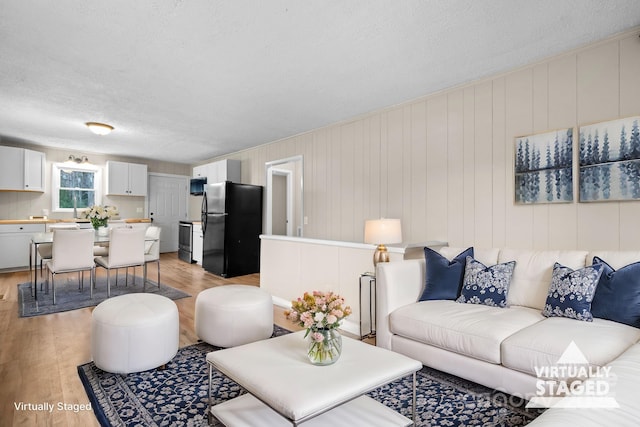 living room featuring wood walls, light wood-type flooring, and a textured ceiling