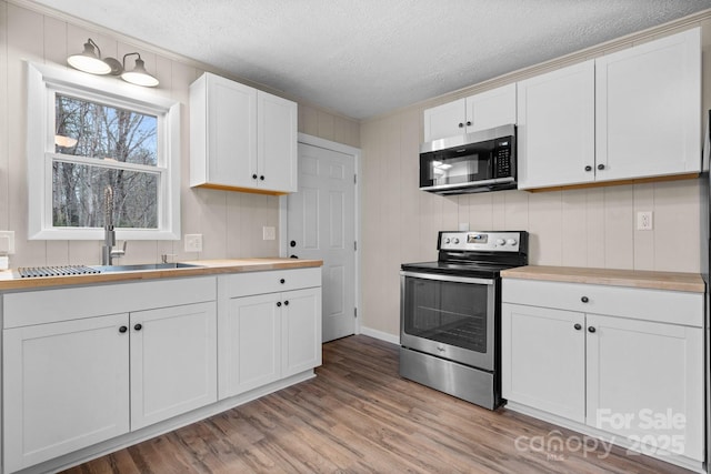 kitchen featuring appliances with stainless steel finishes, a textured ceiling, sink, light hardwood / wood-style flooring, and white cabinets