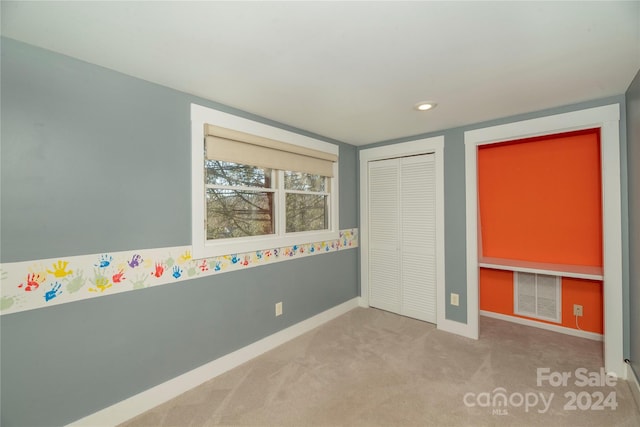 unfurnished bedroom with light carpet and a closet