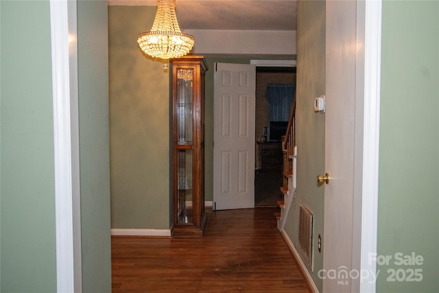 corridor featuring dark wood-type flooring and a chandelier