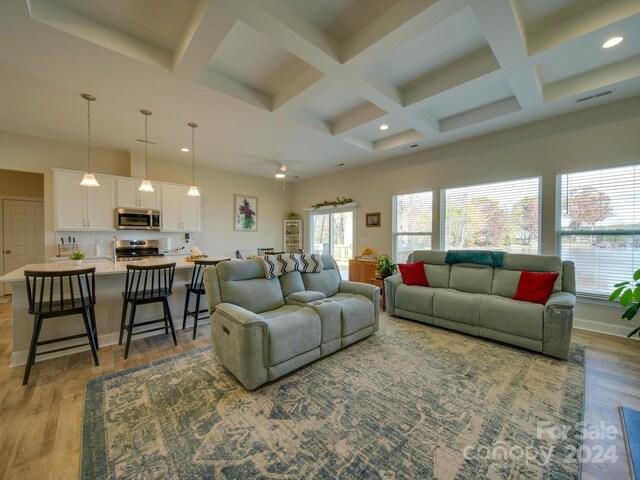 living room with coffered ceiling, beamed ceiling, and light hardwood / wood-style flooring