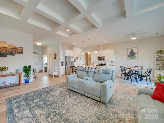 living room featuring beam ceiling, ceiling fan, light hardwood / wood-style floors, and coffered ceiling