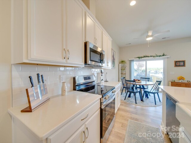 kitchen with appliances with stainless steel finishes, light hardwood / wood-style flooring, white cabinetry, and ceiling fan